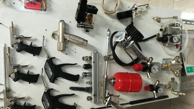 Pannello espositivo bianco con pistole di soffiaggio, raccordi rapidi, riduttori di pressione con manometri e serbatoio rosso